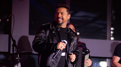 O cantor Xand Avião sorrindo com microfone na mão durante show